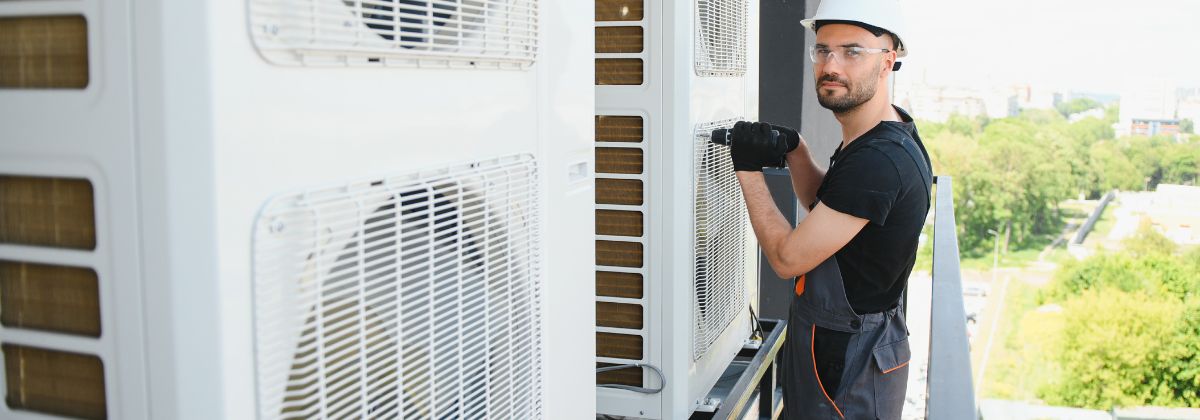 Técnico instalando y revisando una unidad de climatización junto a un equipo exterior en una vivienda