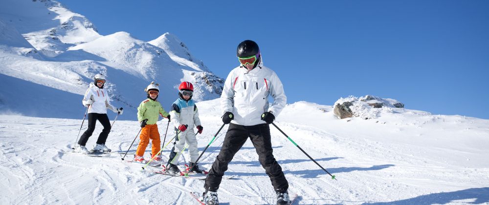 Familia con instructor aprendiendo a esquiar en una estación de esquí para principiantes.