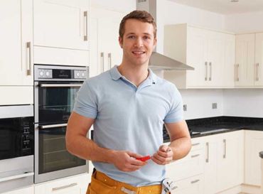 reparador de hogar sonriendo en cocina con herramientas de trabajo 