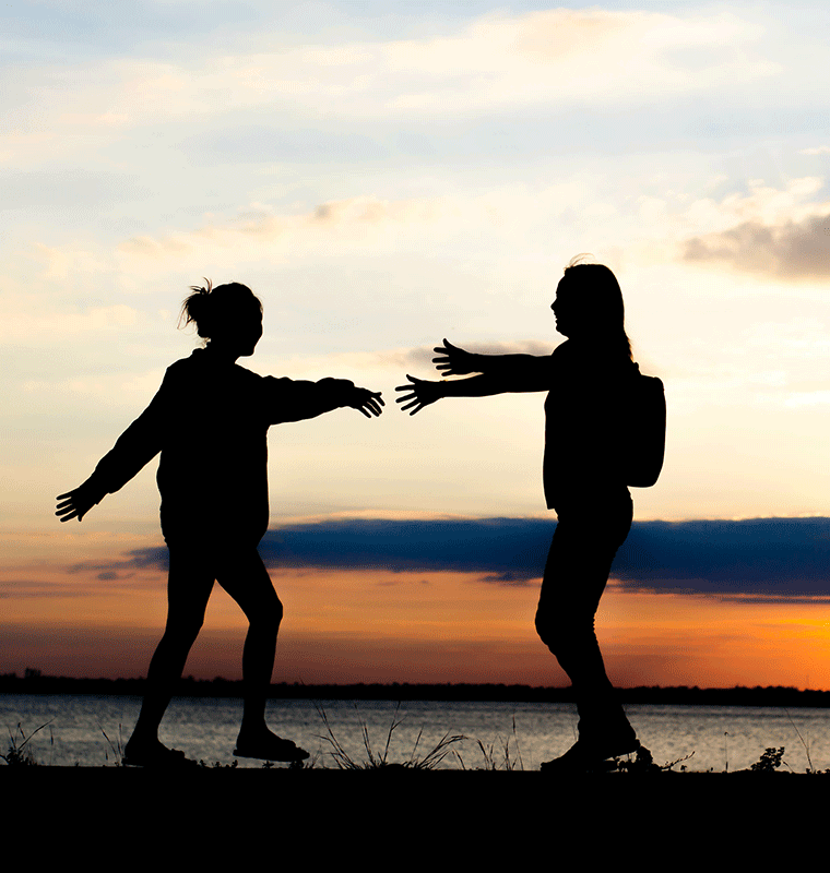 dos personas saltando ante una puesta de sol 
