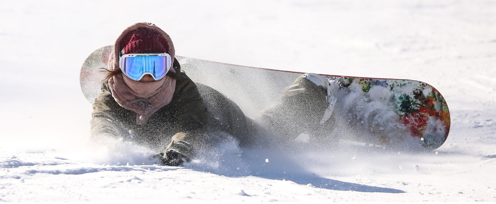 Snowboarder sentado en la nieve sujetándose la muñeca tras una caída