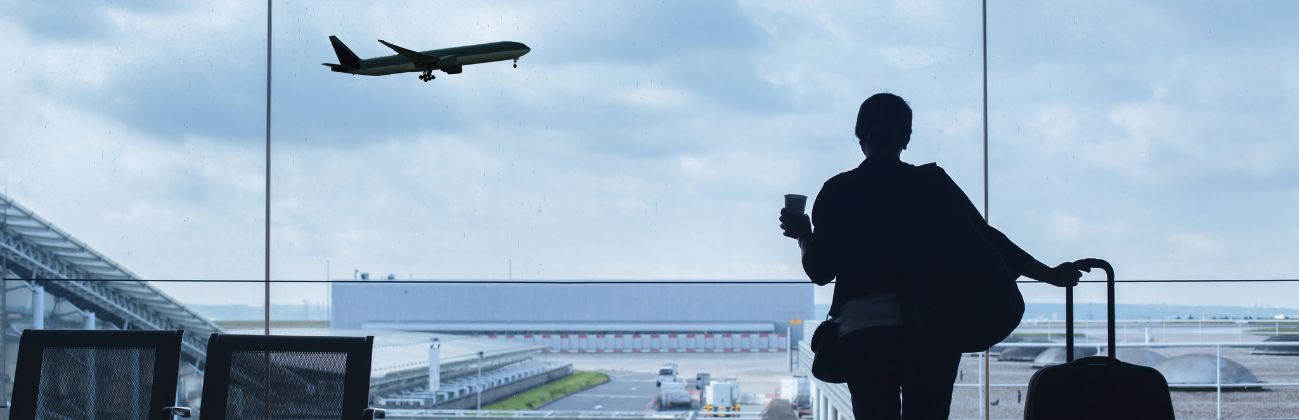 Cinta de equipajes con maleta retrasada y pasajera gestionando la incidencia en el aeropuerto