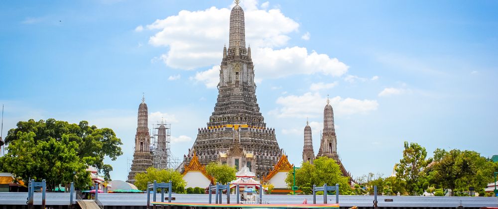 Templo Wat Arun a orillas del río Chao Phraya en Bangkok, con su torre central decorada bajo cielo despejado