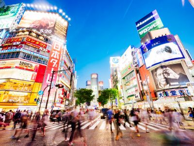 Cruce de Shibuya en Tokio con pantallas luminosas y peatones cruzando simultáneamente